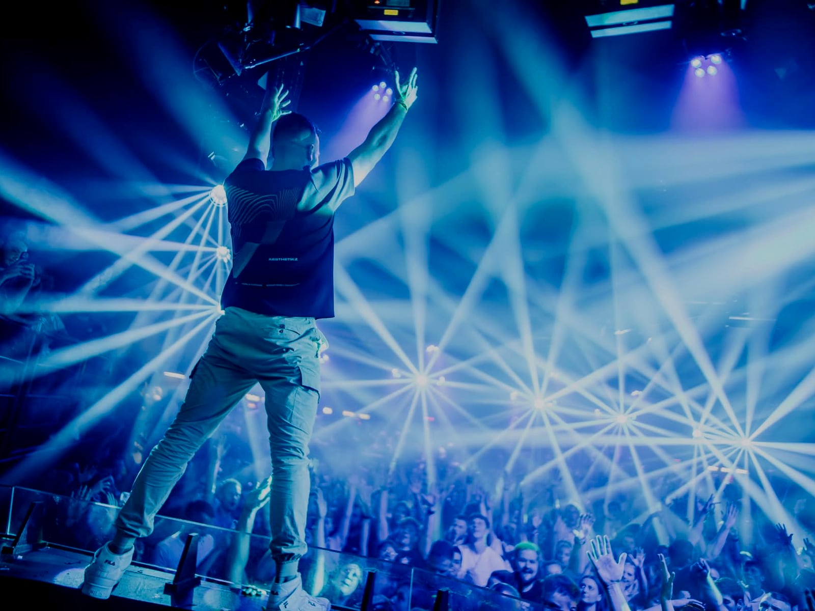 A-RIZE standing on the booth with white laser beams fanning out over the crowd