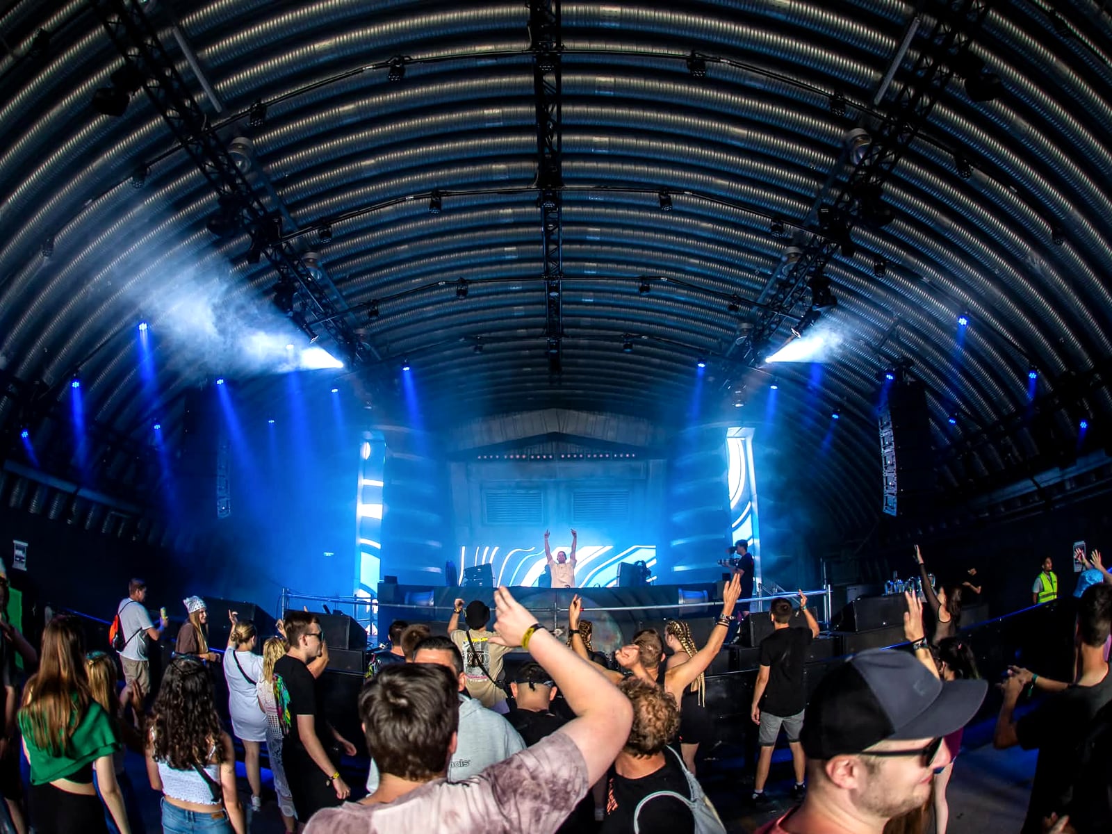 Wide view of the full hall from the crowd, the stage lit at the far end