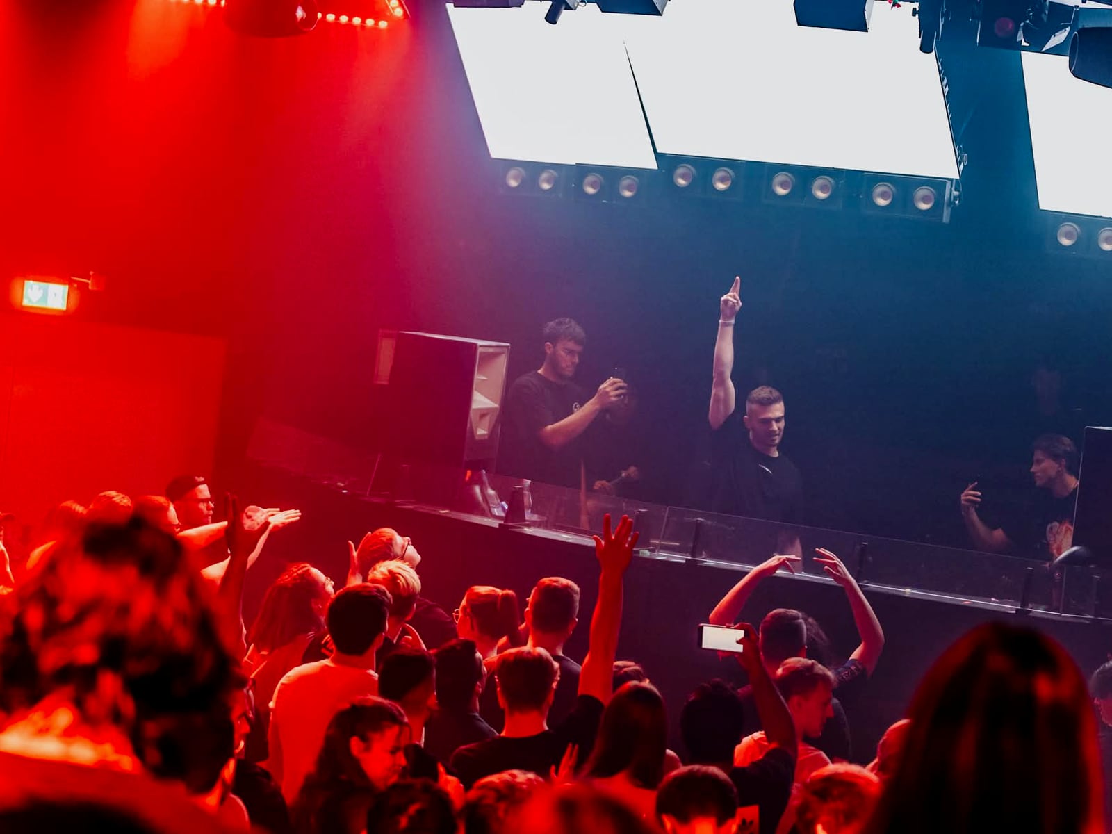 A-RIZE playing to a red-lit room, the crowd pressed up to the booth